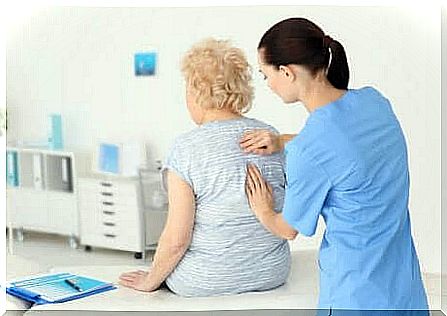 A specialist examining the back of an elderly woman. 