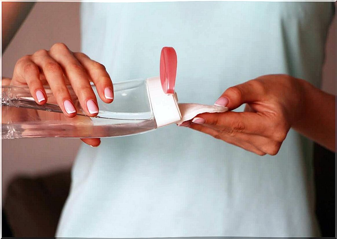 A woman puts micellar water on a cotton pad.